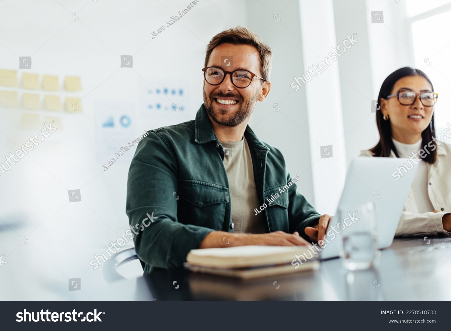 Happy business man listening to a discussion in an office boardroom. Business professional sitting in a meeting with his colleagues. #2278518733