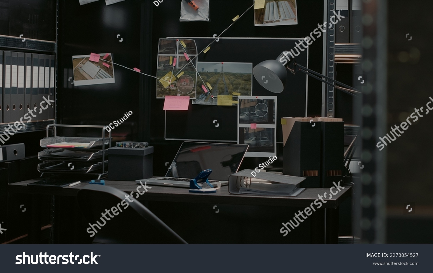 Evidence room office with detective board and desk, crime scene photos and case files on walls. Empty police inspector archive space with crime suspects, witness statements and sticky notes. #2278854527