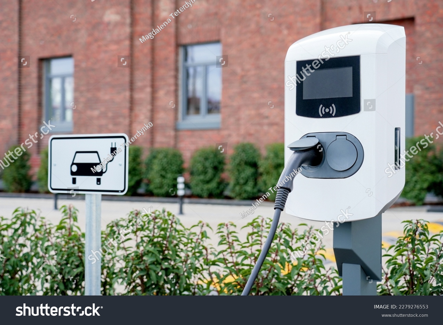 e-car charging station, e-car charge point or electric vehicle supply equipment (EVSE) with information sign electric car public charging point station and charge cable, charging plug parking spaces #2279276553