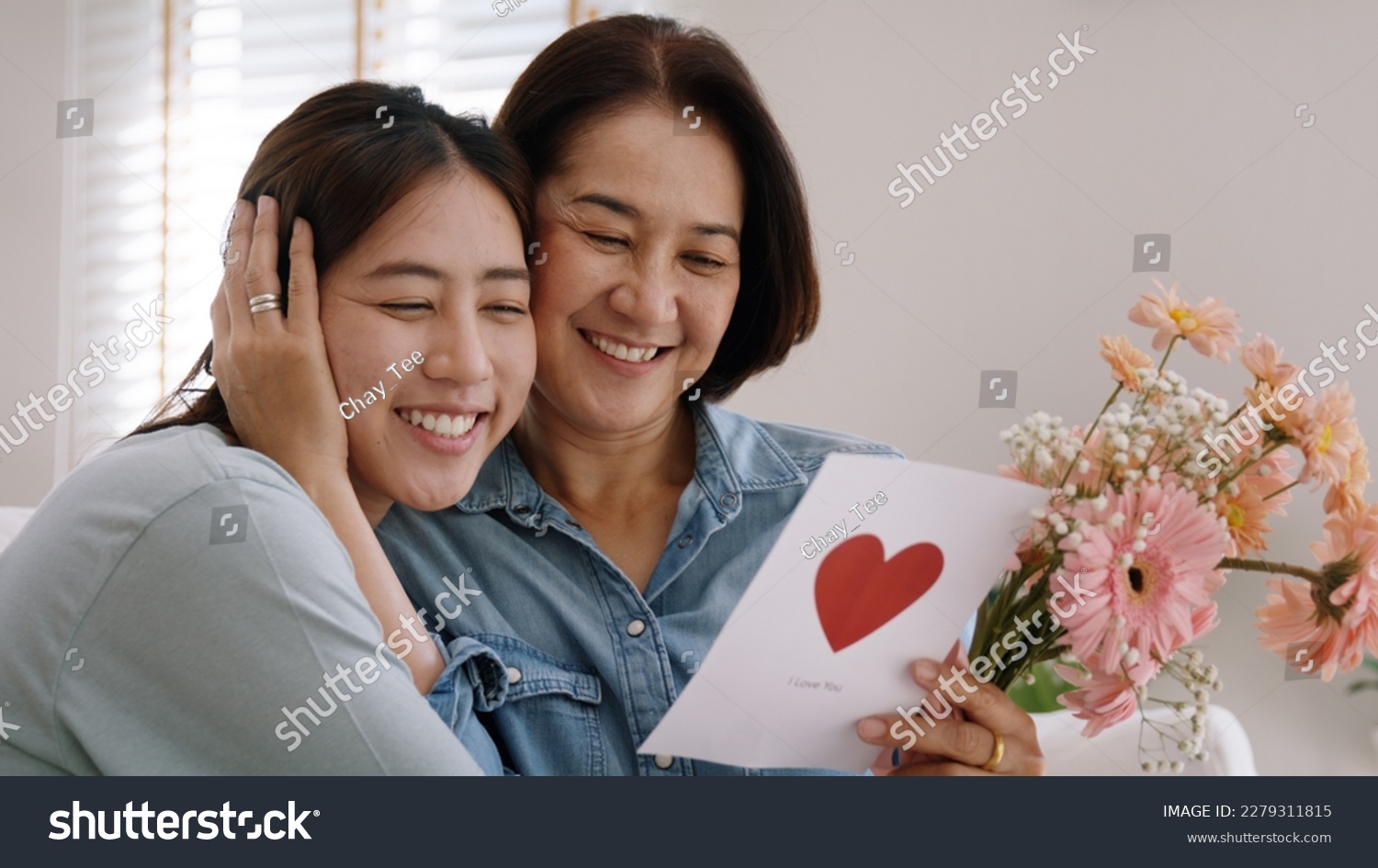 May Mother's day young adult grown up child cuddle hug give flower gift box red heart card to mature middle aged mum. Love kiss care mom asia people sitting at home sofa happy smile enjoy family time. #2279311815