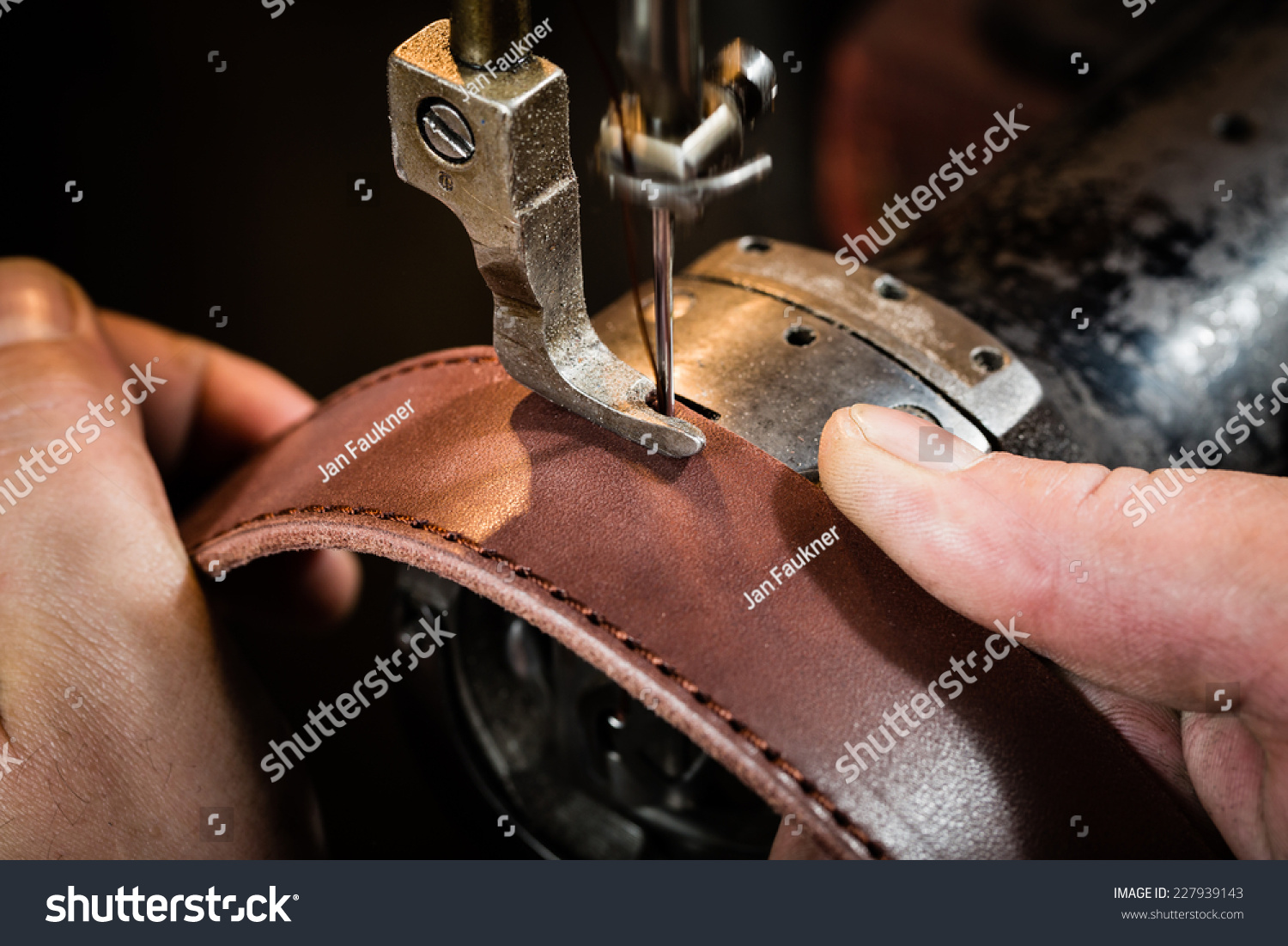 Sewing process of the leather belt. Man's hands behind sewing. Leather workshop. #227939143