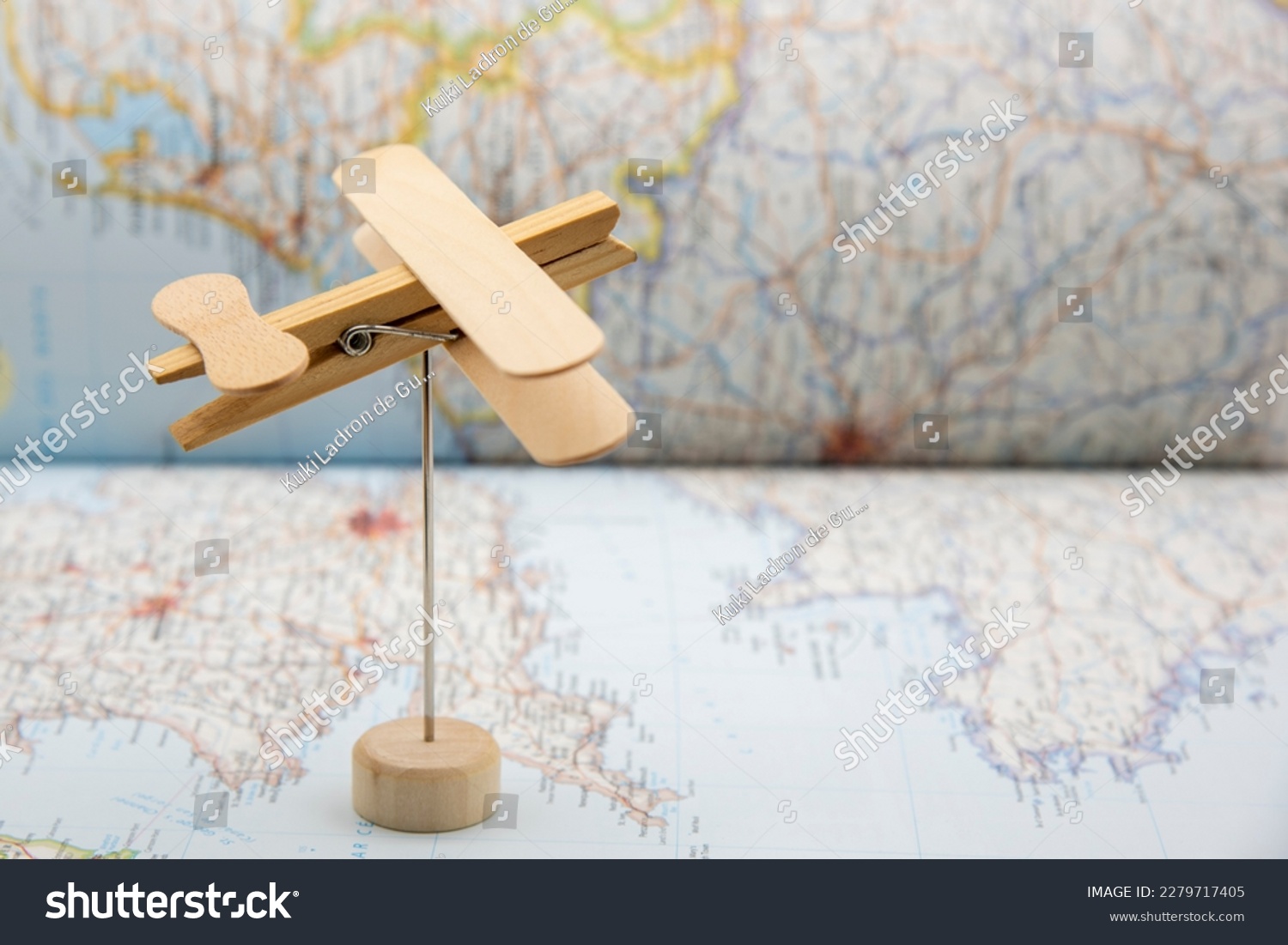 Wooden plane made with ice cream sticks and a clothespin, flying over a map #2279717405