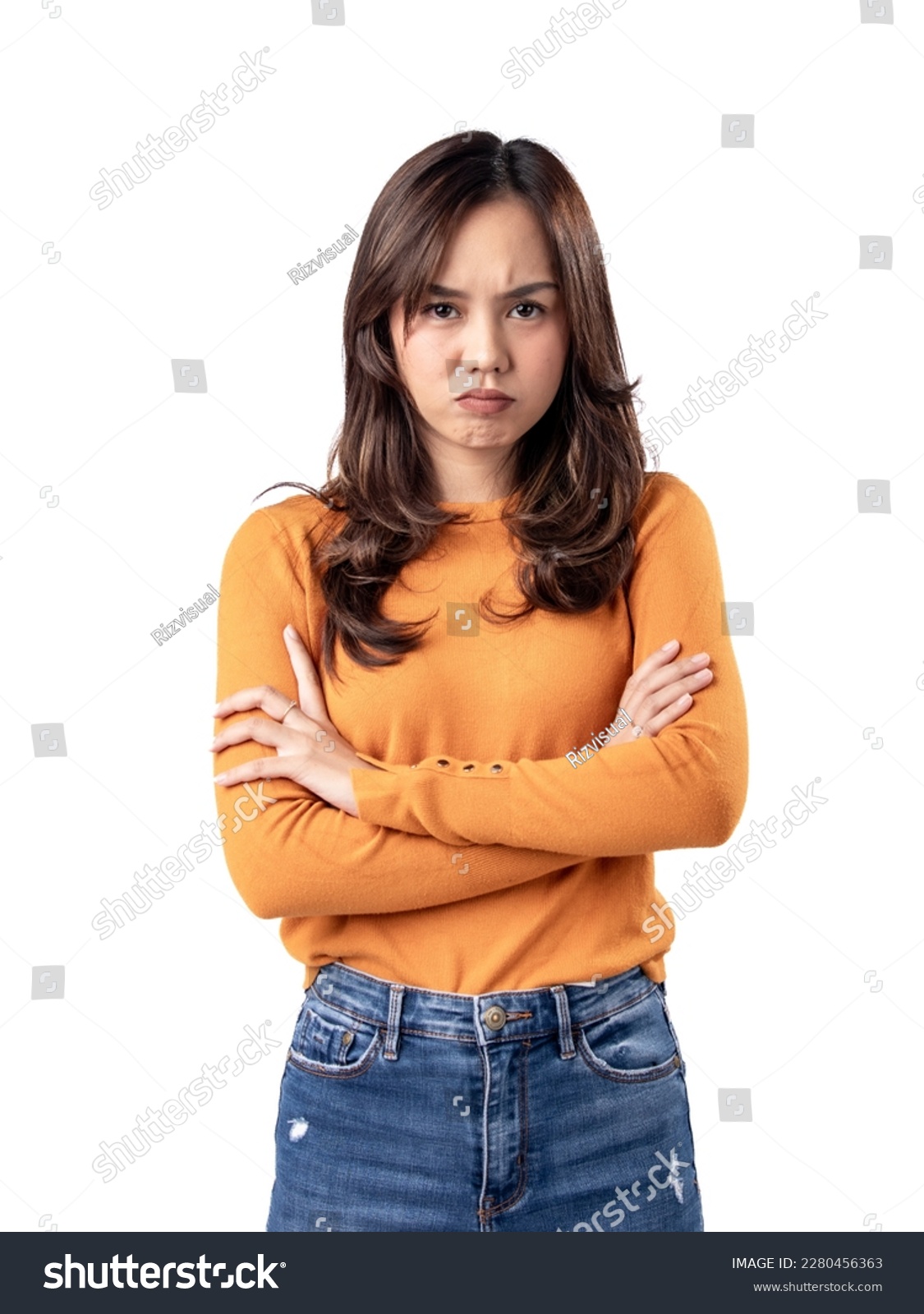 A portrait of an Asian Indonesian woman wearing an orange sweater and looking unhappy, folding her arms, isolated on a white background #2280456363