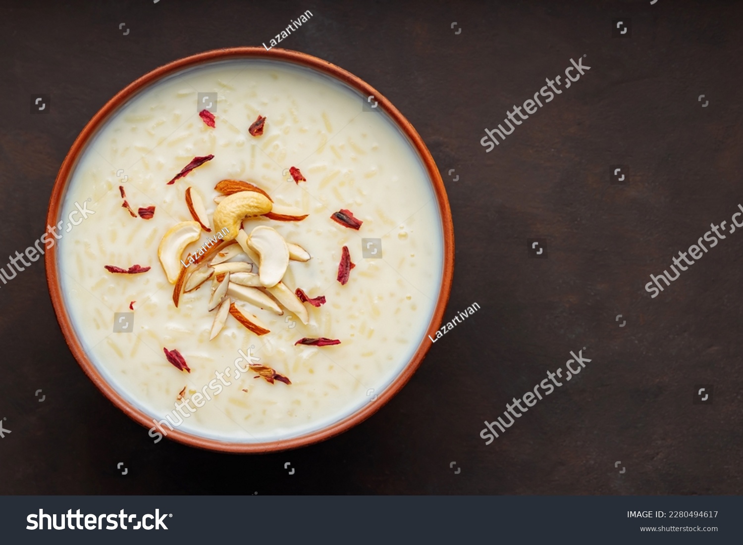 Bowl with rice pudding on dark background. Creamy rice kheer with cashew nuts and almonds. Copy space. Top view #2280494617