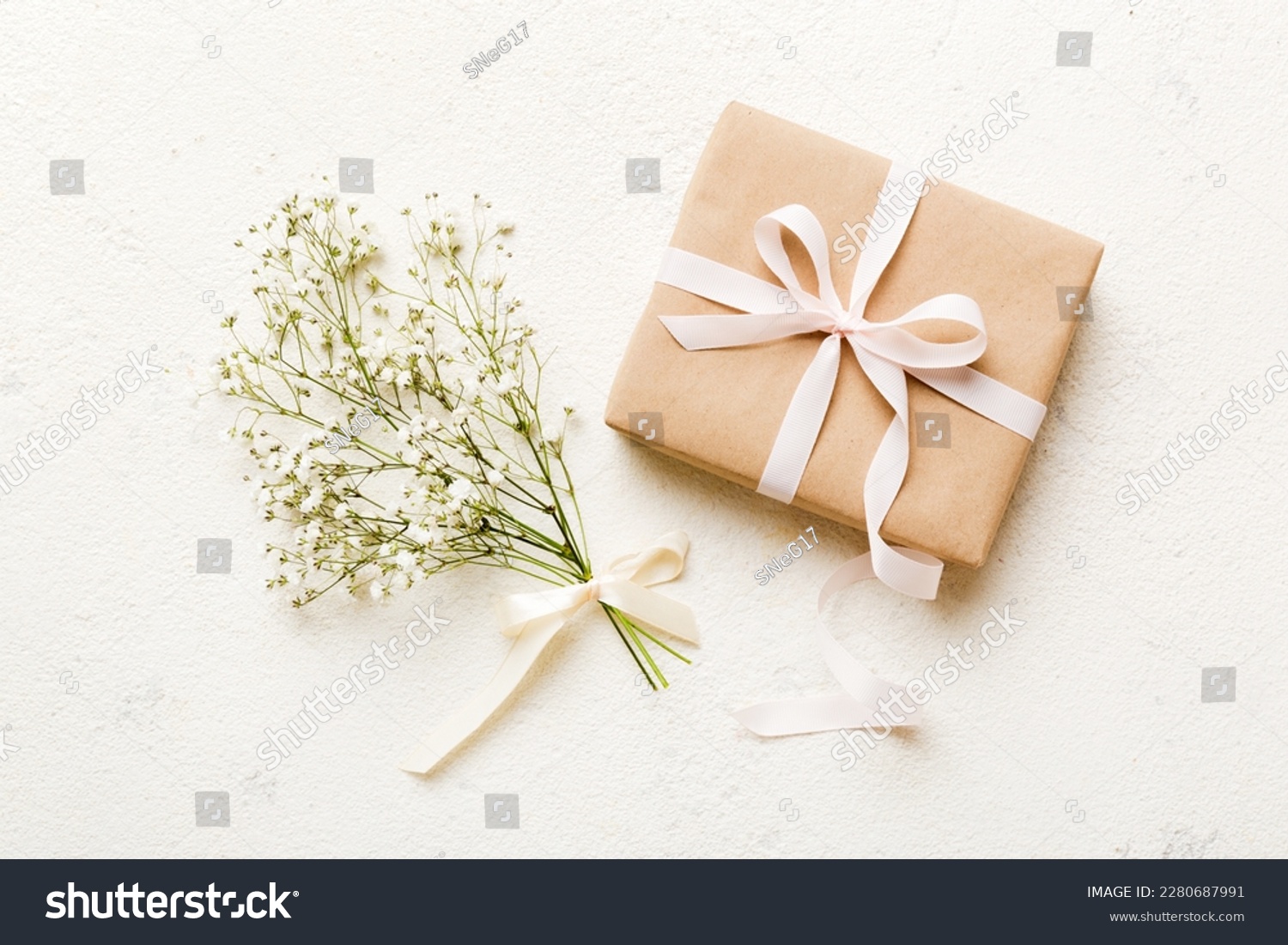 Gift or present box and flower gypsophila on light table top view. Greeting card. Flat lay style with copy space. #2280687991