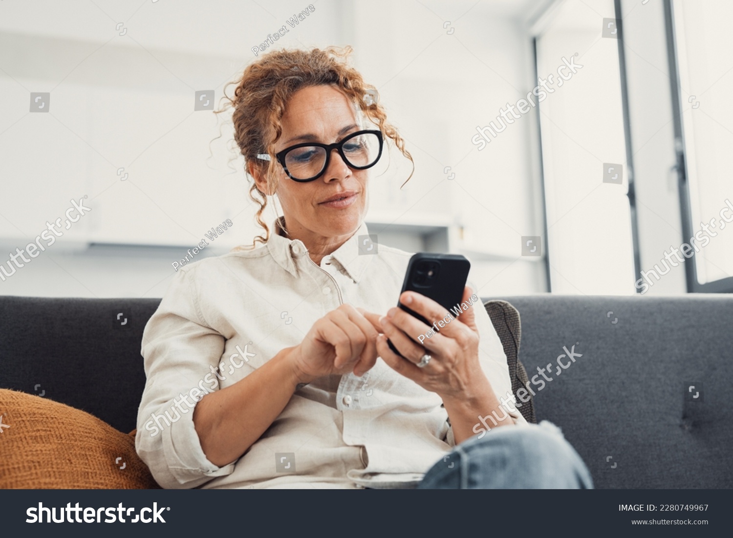 Excited happy young adult woman reading message on mobile phone, getting good news on screen, smiling, laughing, talking on video call, chatting on Internet, using online app. Communication concept #2280749967