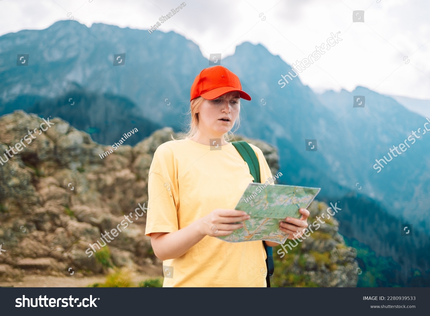 Shot of a young lost woman holding a map while taking in the view from the top of a mountain. Girl tourist in mountain read the map. Poland, Tatry  #2280939533