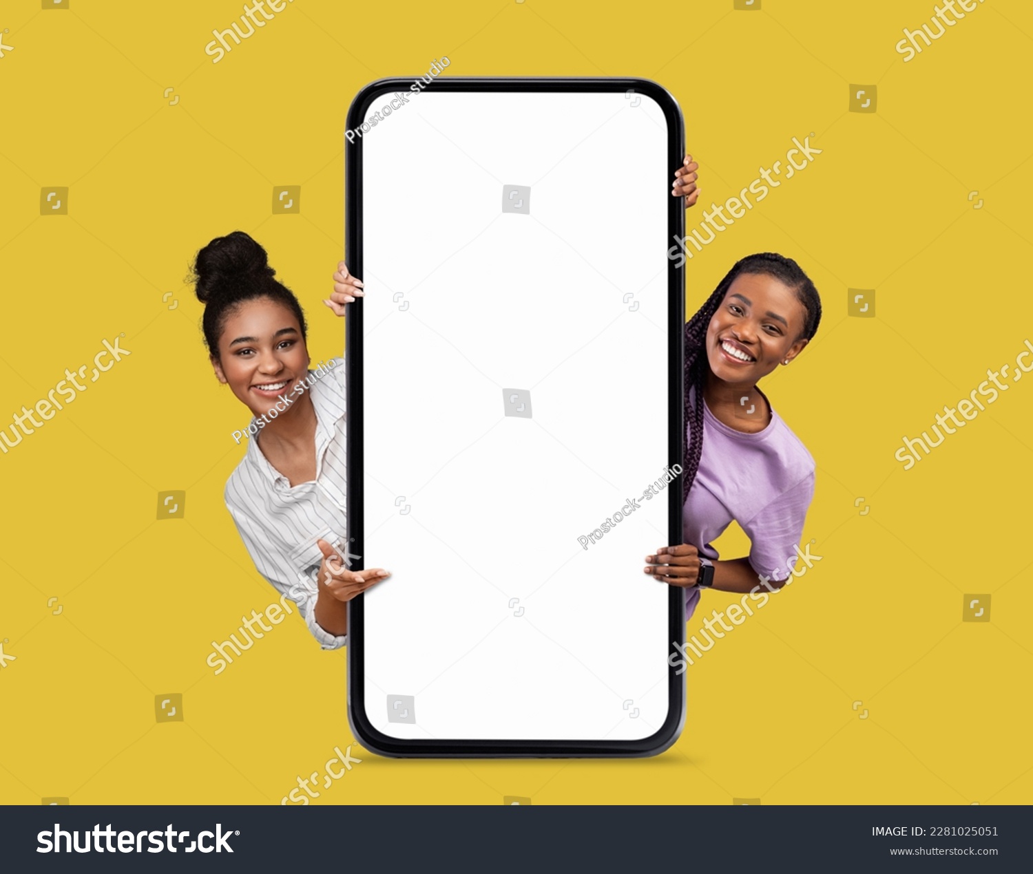 Online Offer. Two Beautiful Smiling Black Women Peeking Out Behind Big Blank Smartphone With White Screen Isolated Over Yellow Background, African American Females Showing Copy Space, Collage, Mockup #2281025051