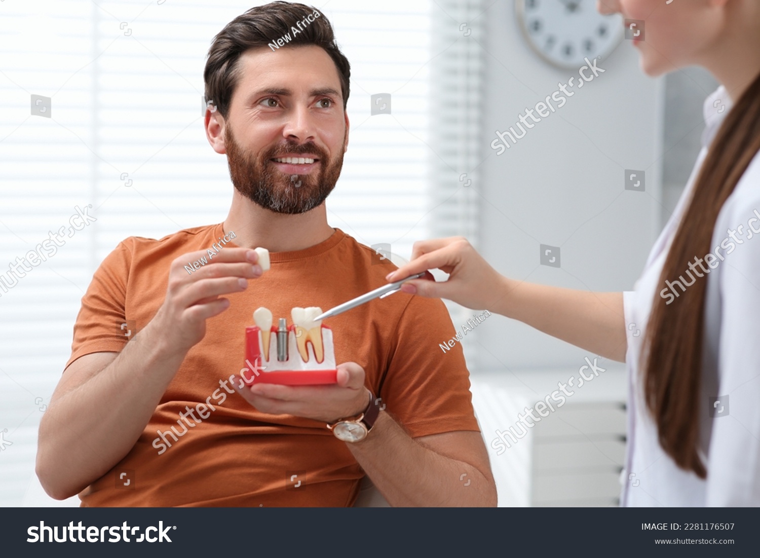 Doctor with educational model of dental implant consulting patient in clinic #2281176507