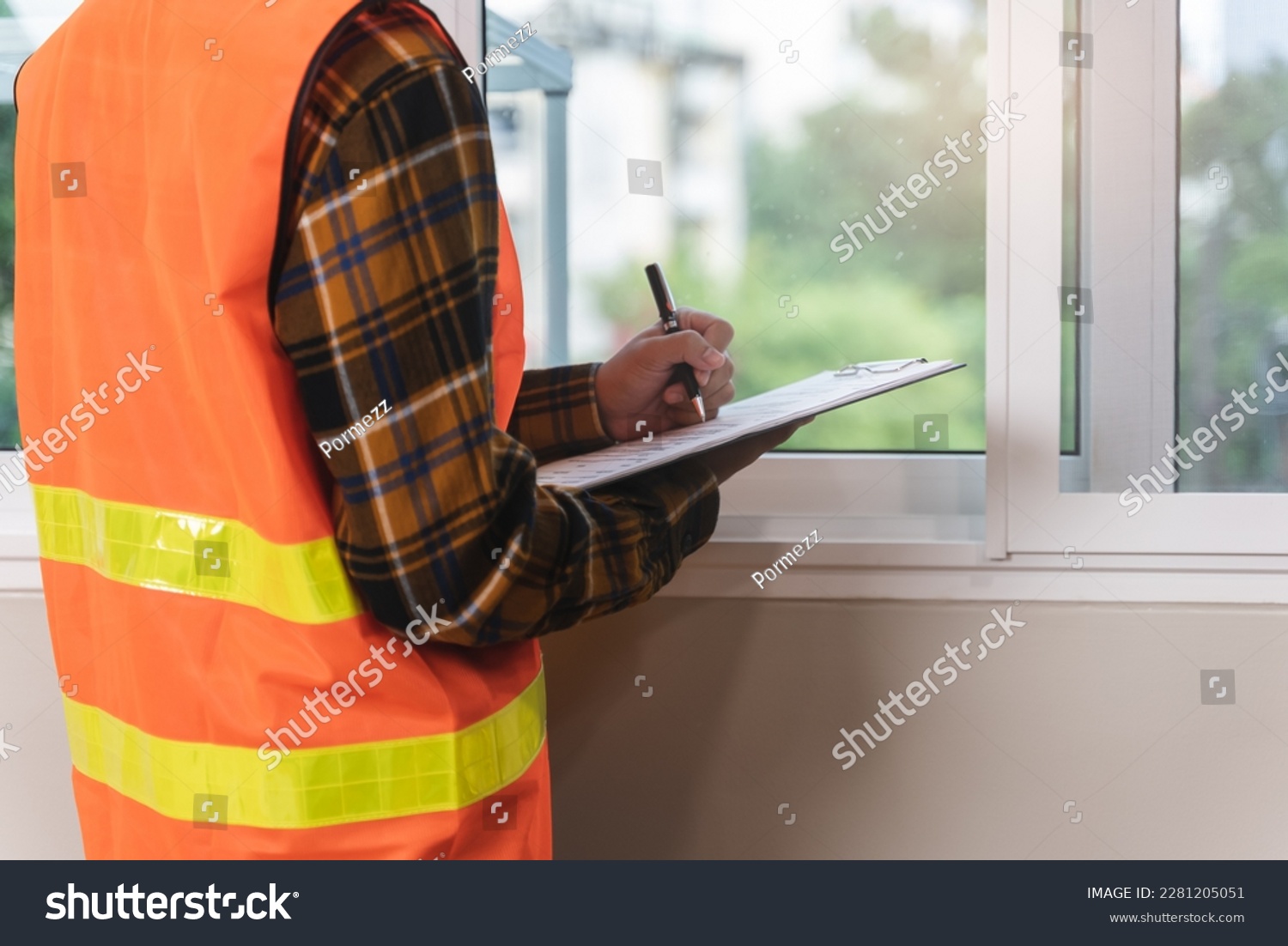 Asian inspector checking structure of new property and taking note in the clipboard for review and fix the house before sell to client #2281205051