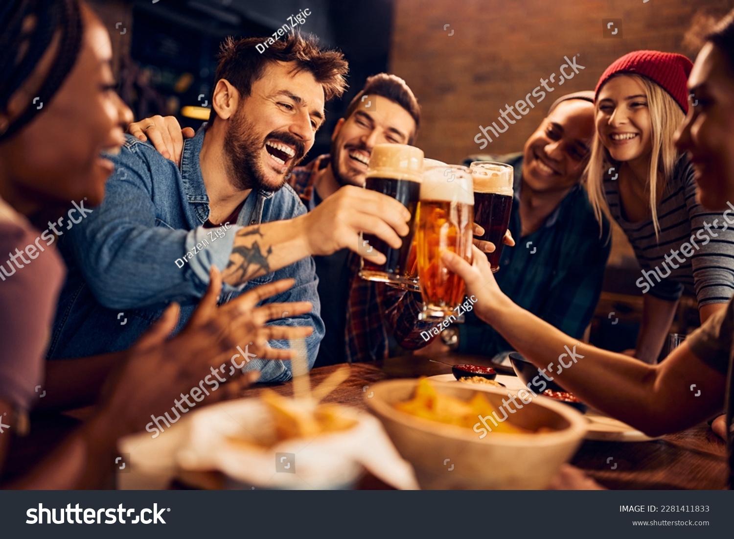 Multiracial group of happy friends having fun while toasting with beer in a bar. #2281411833