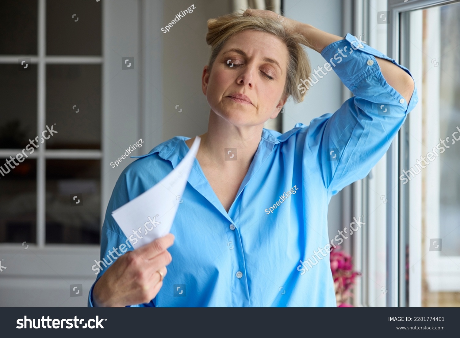 Menopausal Mature Woman Having Hot Flush At Home Cooling Herself With Letters Or Documents #2281774401
