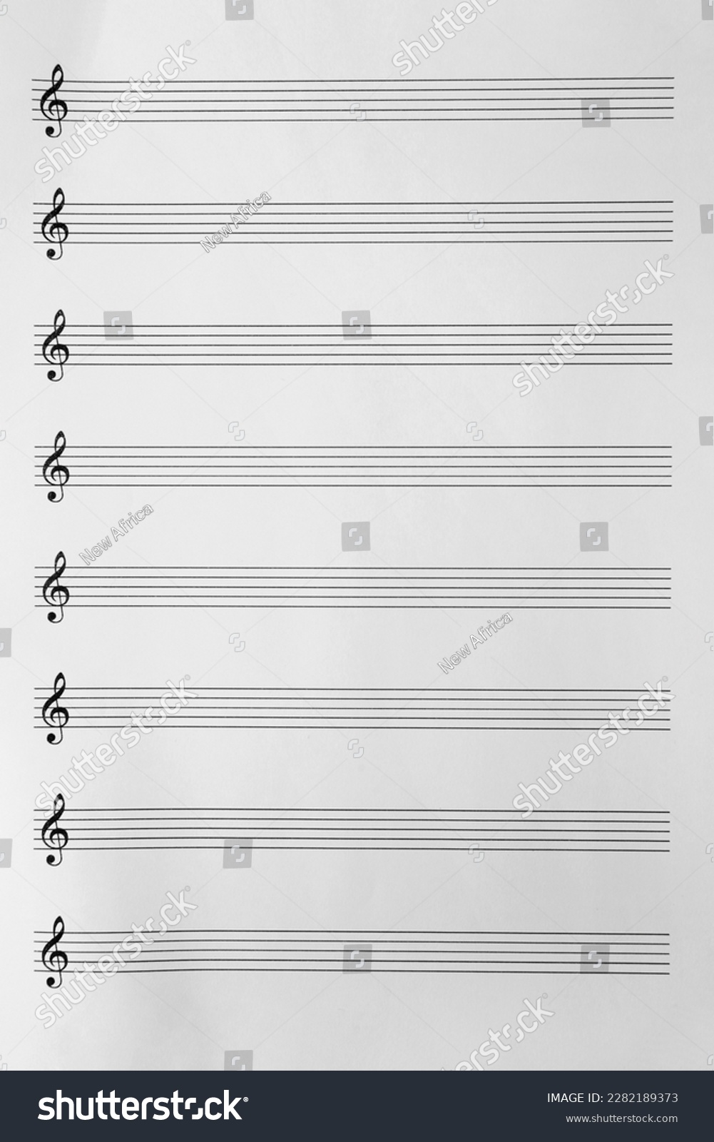 Sheet with empty staves for music notes and treble clef as background, top view #2282189373