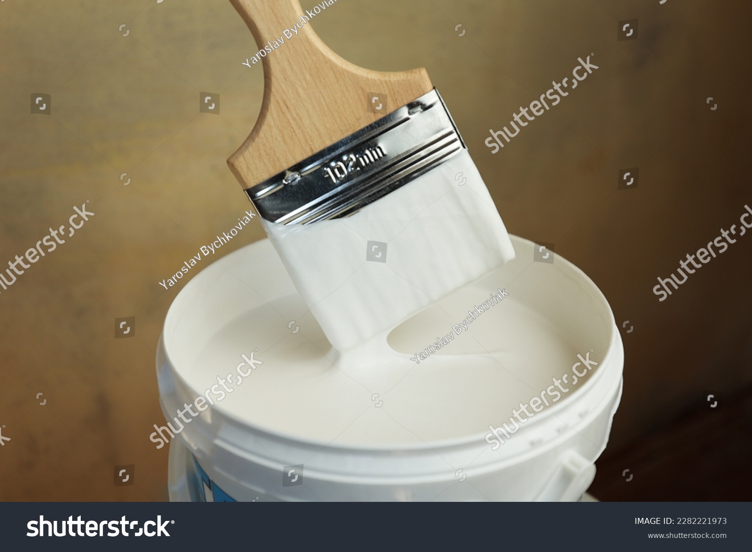 A bucket of white paint and a brush. Painting works in the premises. Tidying up the apartment. Repair of premises. The brush is dipped in white paint #2282221973