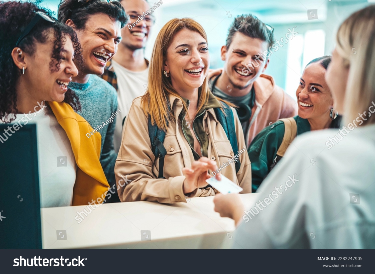 Group of young people takes room key card at check-in of youth hostel guest house - Happy tourists talking with receptionist at hotel lobby - Summer vacations and tourism concept #2282247905
