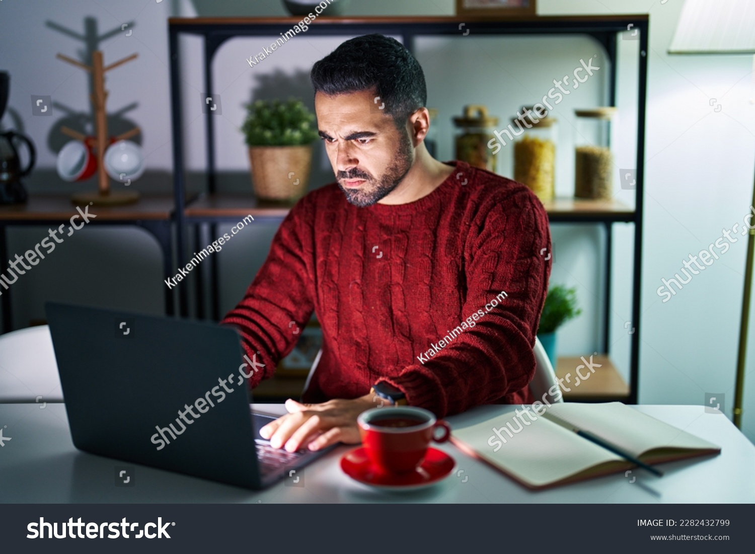 Young hispanic man with beard using computer laptop at night at home skeptic and nervous, frowning upset because of problem. negative person.  #2282432799
