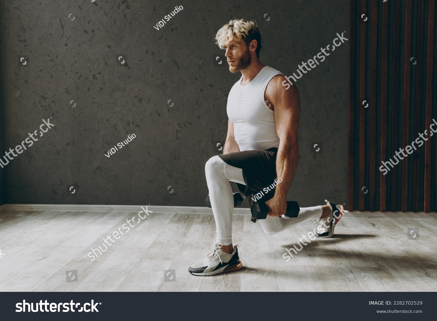 Full body side view caucasian young strong sporty athletic sportsman man wear white tank shirt black shorts lifting hold dumbbells do squat lunges warm up training indoor at gym. Workout sport concept #2282702529