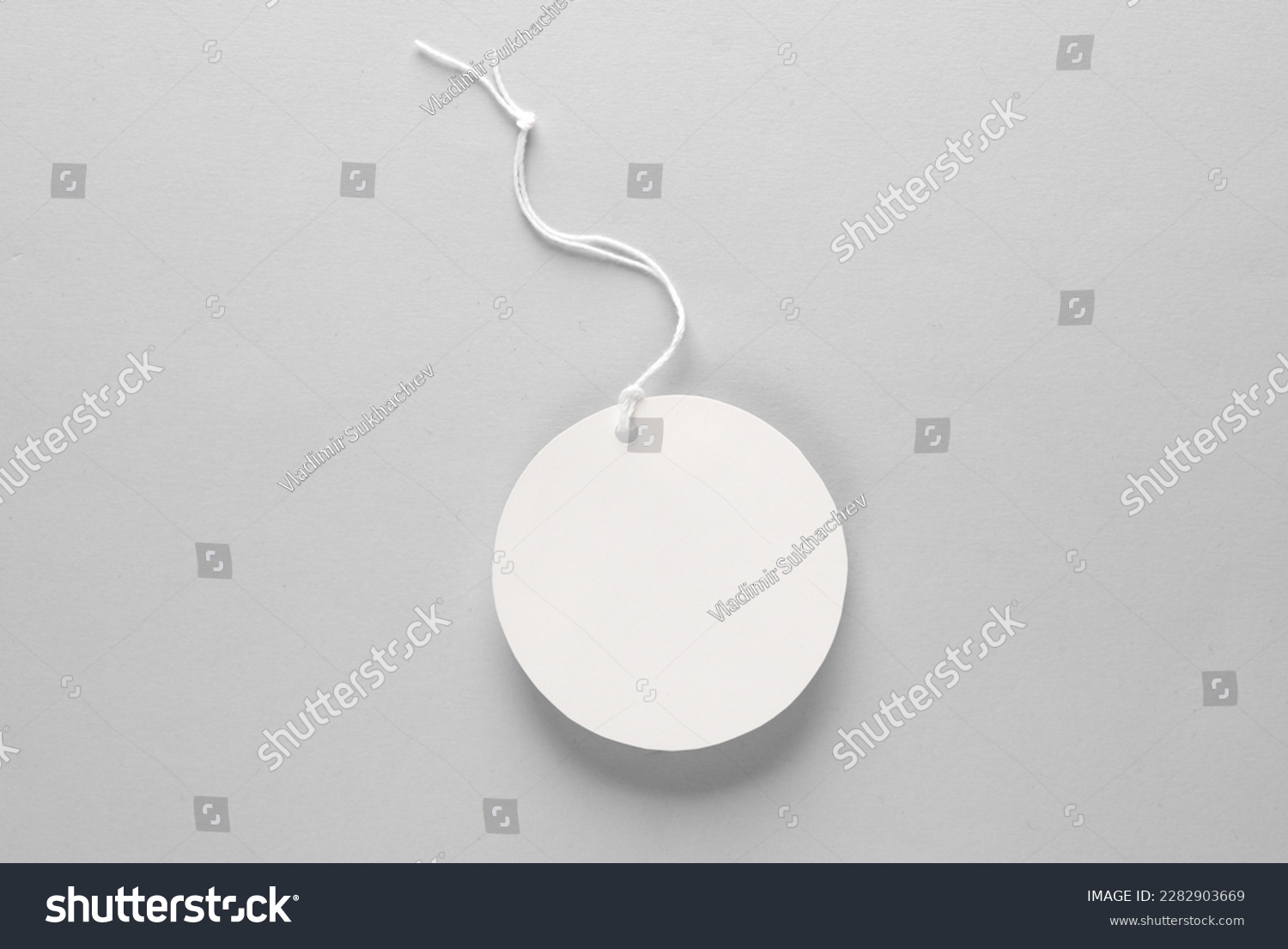 Round empty white price tag with string on gray background. Template for design #2282903669