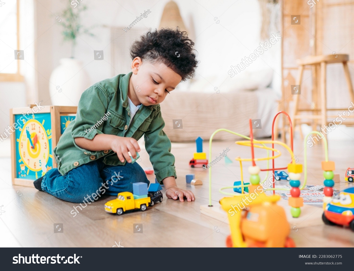 Concentrated little african american boy playing toys sitting on warm floor in modern living room. Baby development. Small tower. Learning creative concept #2283062775