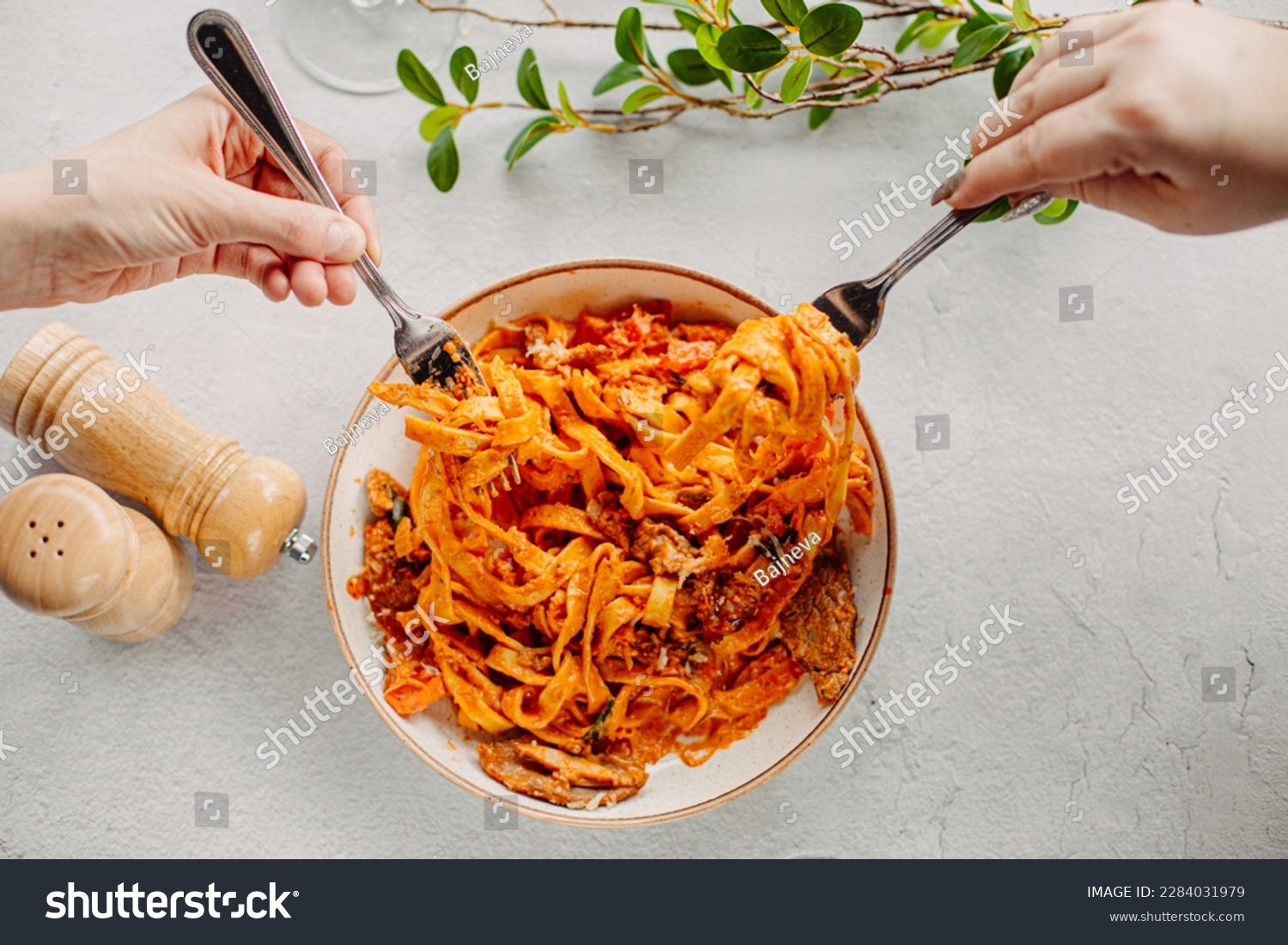 Italian pasta, tomato sauce. Two female hands in the frame, girls eat pasta, hold forks in their hands, top view, Italian cuisine. #2284031979