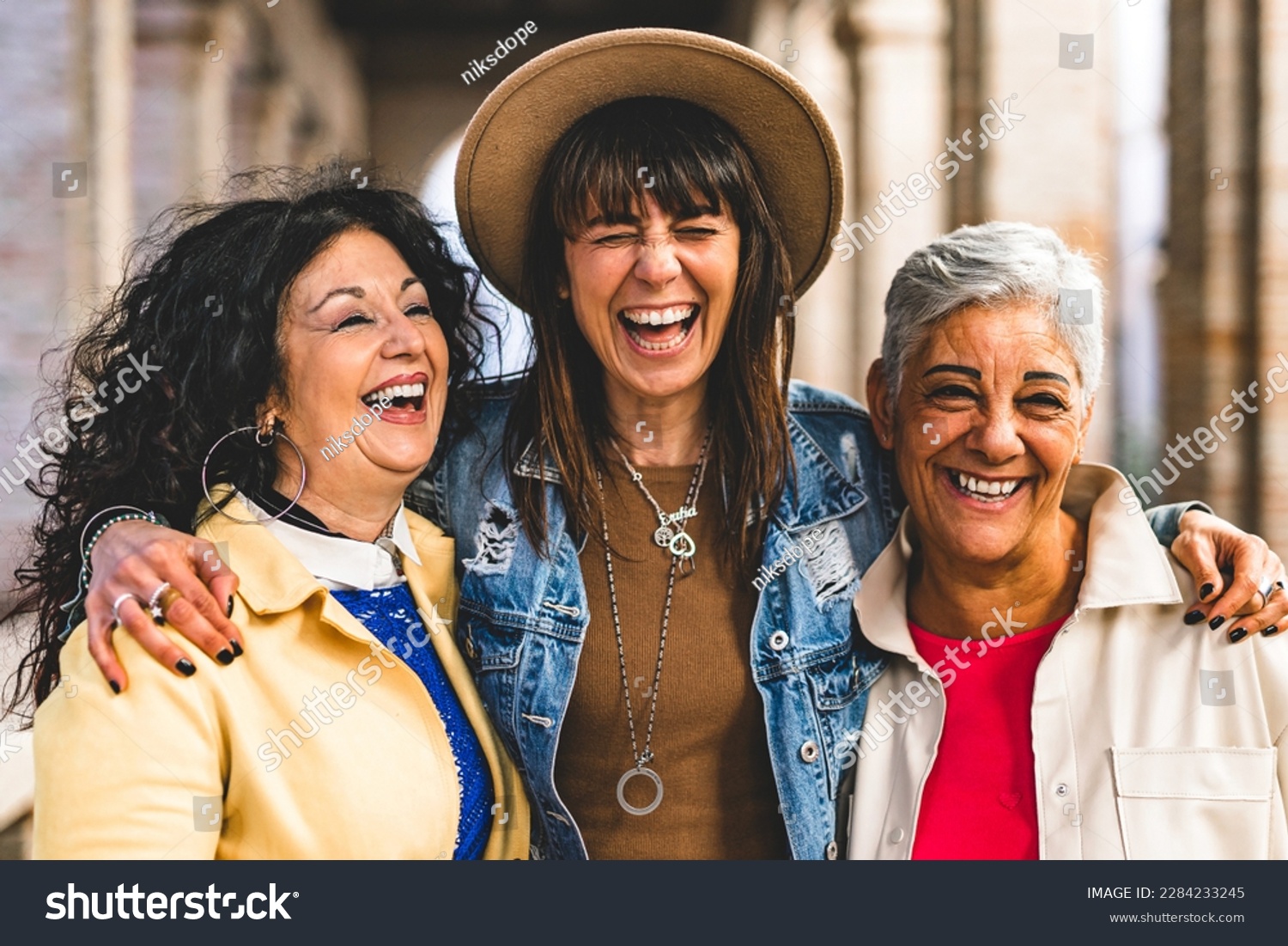 Multiracial senior women having fun together outdoor at city street- three happy mature trendy female friends hugging and laughing on urban place- Friendship lifestyle concept with elderly people #2284233245