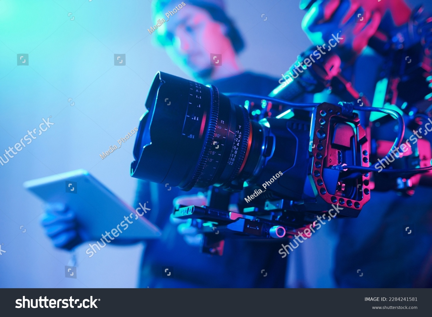 Close-up of operator using professional camera during shooting with director controlling the process #2284241581