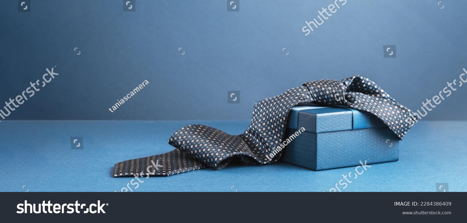 Happy Fathers Day background banner. Two blue gift boxes with ribbon bow and necktie on dark blue table. Monochrome. Gift delivery for him. Male fashion #2284386409