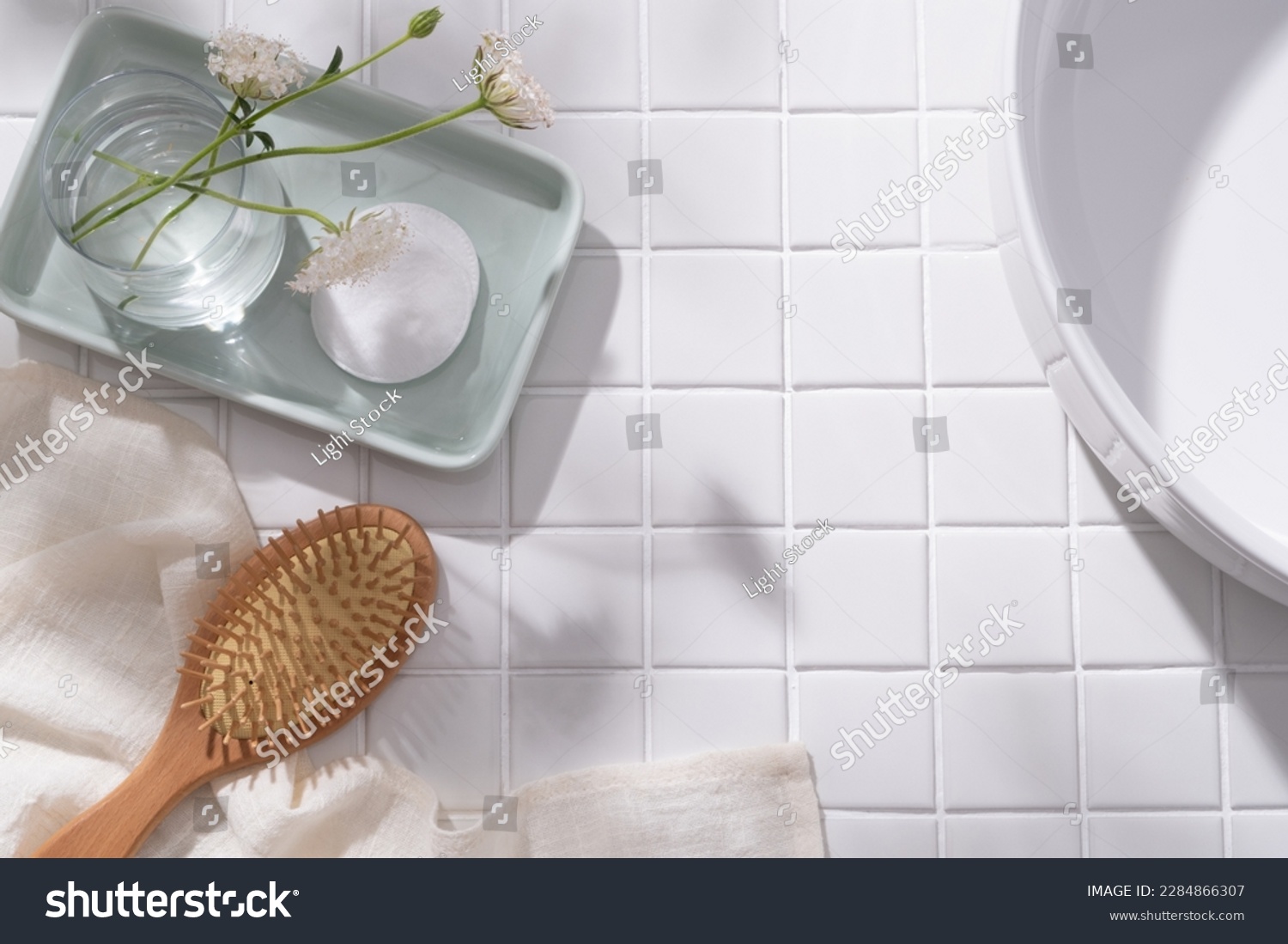 A pastel tray in rectangle shape with a flower vase and a cotton pad placed on, wooden brush with towel and wash basin displayed. Blank space for cosmetic product promotion #2284866307
