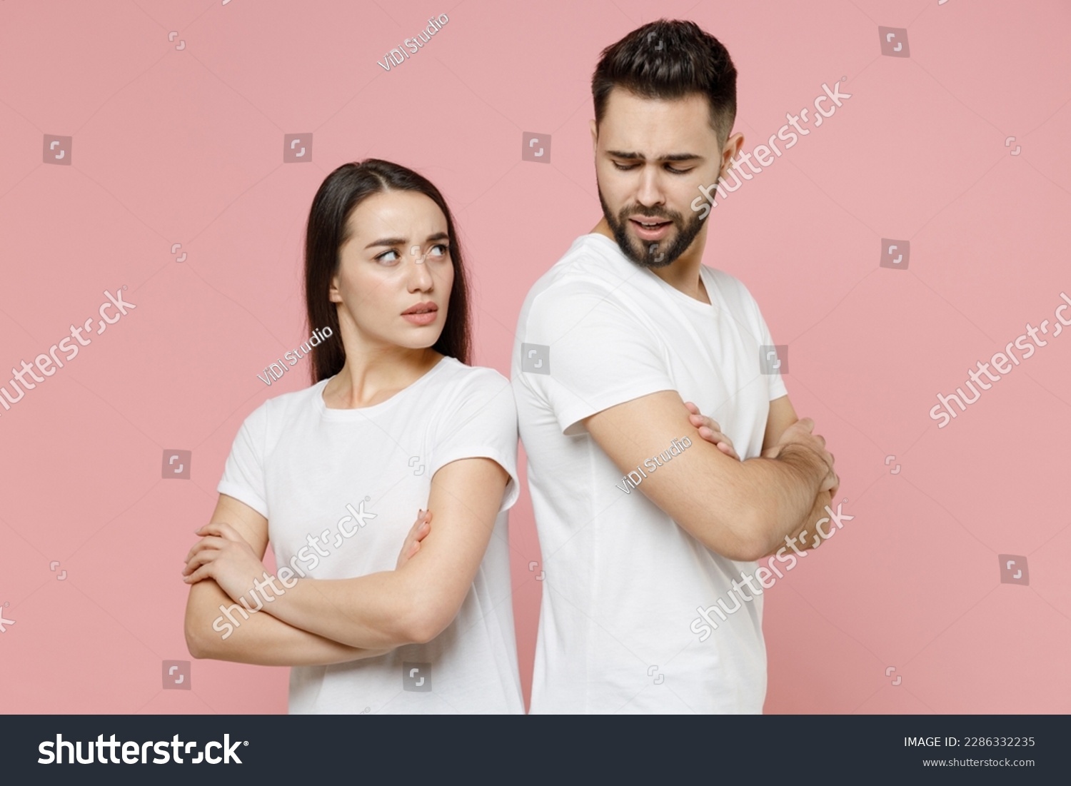 Young irritated dissatisfied couple two friends man woman in white basic t-shirts quarrel swearing have problem stress need family psychologist isolated on pastel pink color background studio portrait #2286332235
