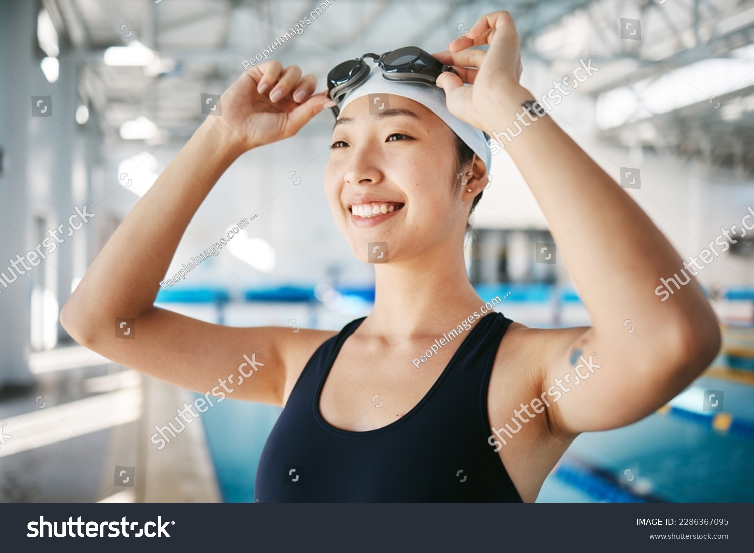 Professional swimming, asian woman with smile and goggles at pool for training, wellness and winner mindset. Water sports, workout and champion athlete swimmer at competition with smile and happiness #2286367095