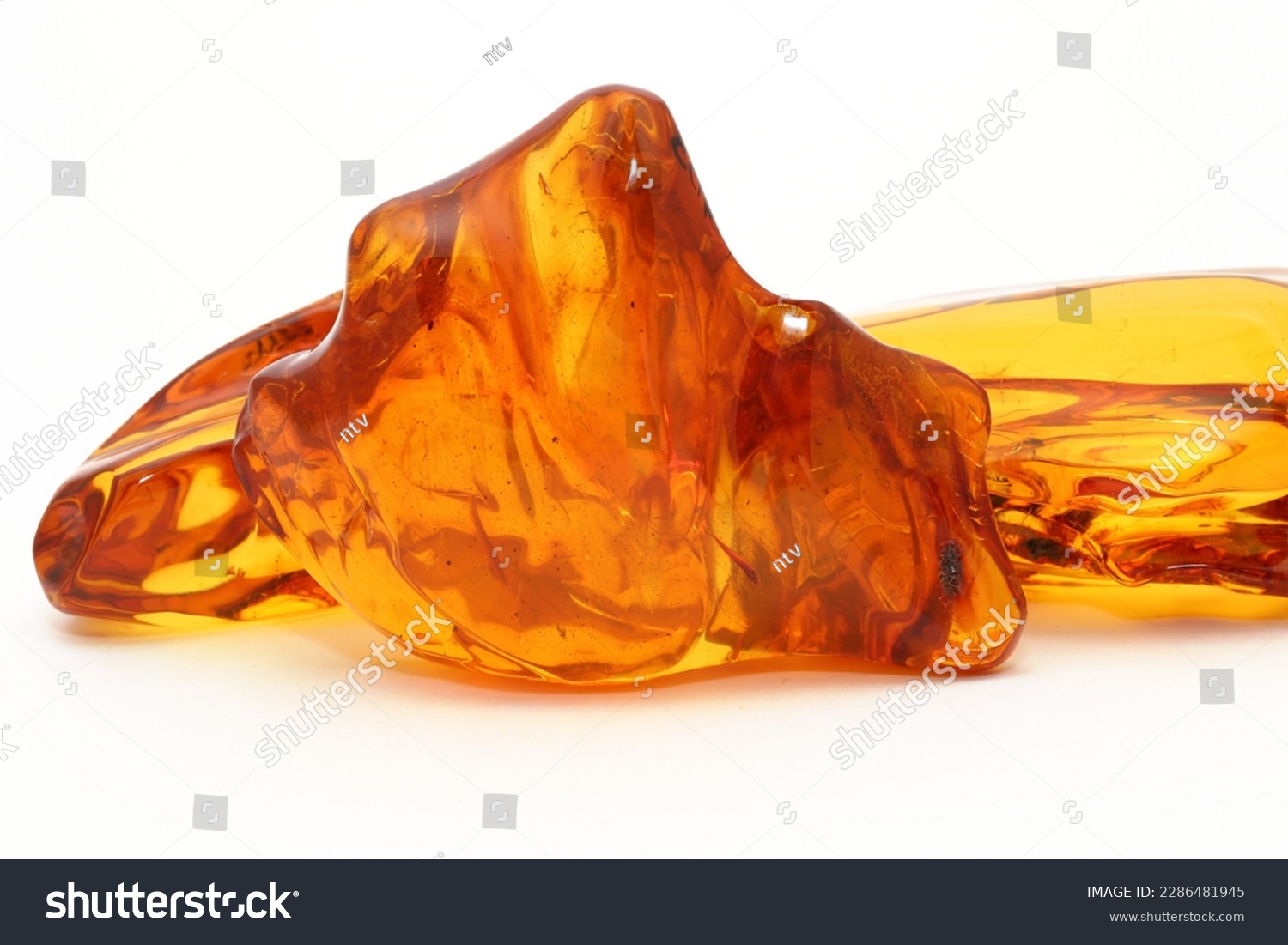  Transparent polished amber on a white background. Copal. Ancient fossil resin. Precious mineral. Patterns in amber. Natural material for jewelers. Science and geology. #2286481945