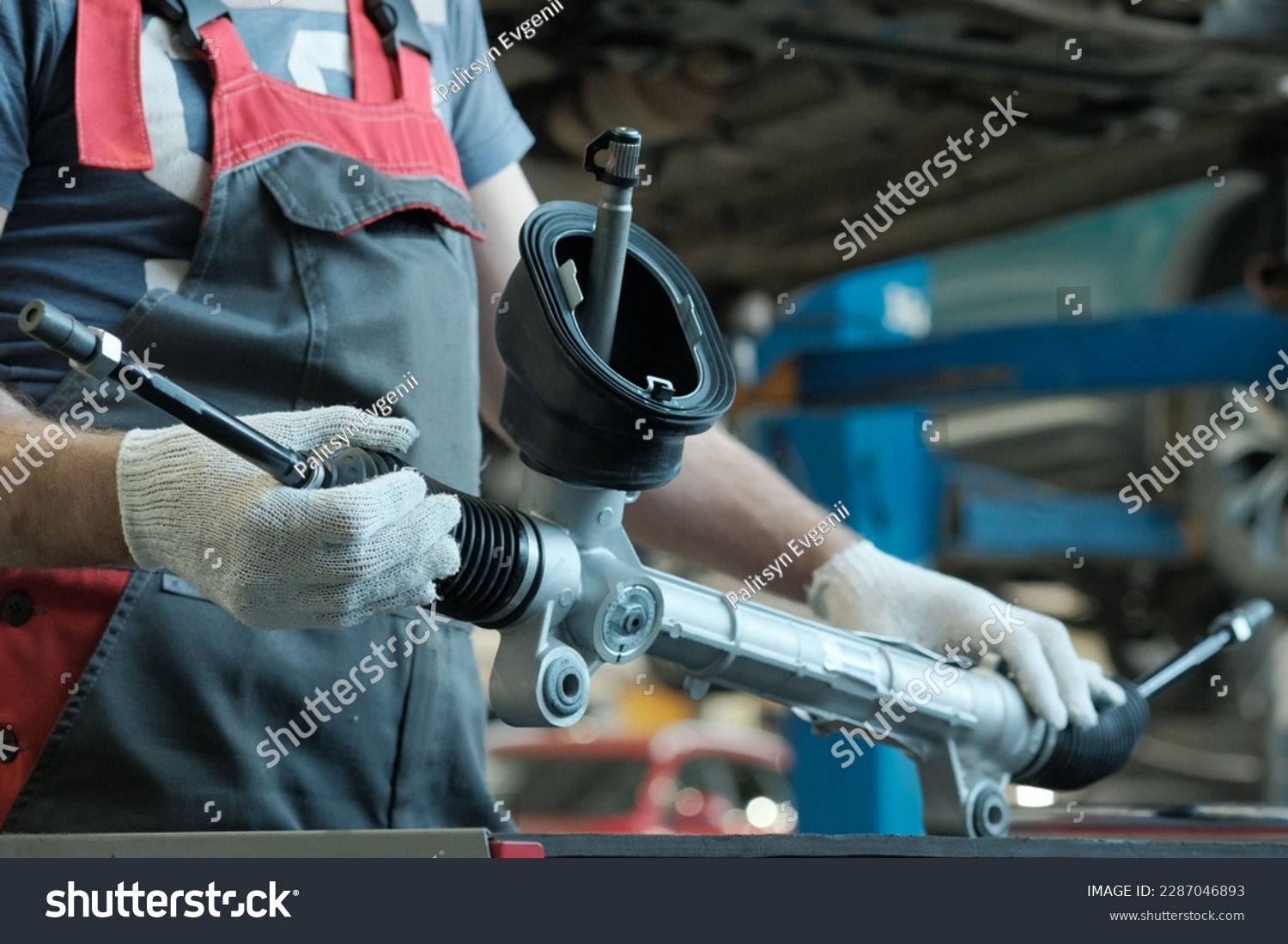 The steering rack is in the hands of an auto mechanic. A component of the hydraulic power steering of the car. Monitoring of the technical condition of the new spare part before installation. #2287046893