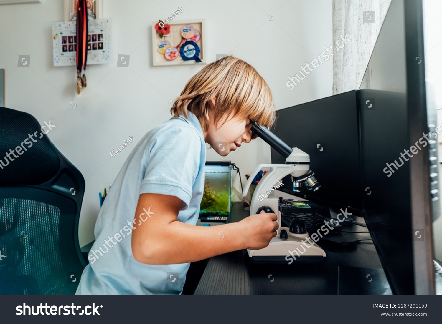 Caucasian boy using a microscope at home at his study place. Child curiosity, thirst for knowledge, home learning experience, home remote education concepts. Selective focus. #2287291159