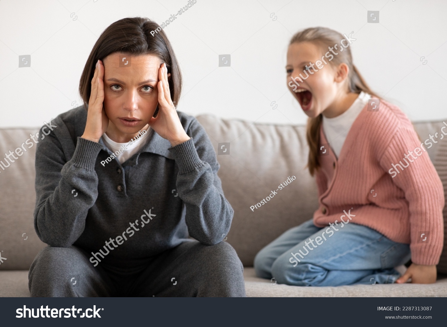 Angry excited aggressive teenager european girl yelling at sad tired millennial woman in living room interior. Relationship problems between mother and daughter, quarrel, hysteria #2287313087