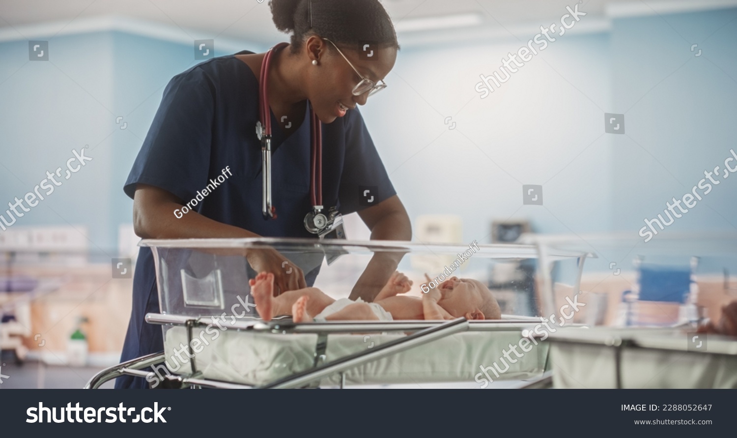 Professional African Nurse Soothing an Adorable Small Caucasian Newborn Child in Nursery Clinic. Medical Health Care, Maternity Hospital and Parenthood Concept #2288052647