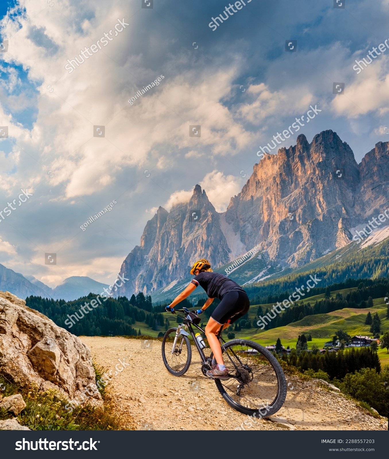 Woman ride electric mountain bikes in the Dolomites in Italy. Mountain biking adventure on beautiful mountain trails. #2288557203