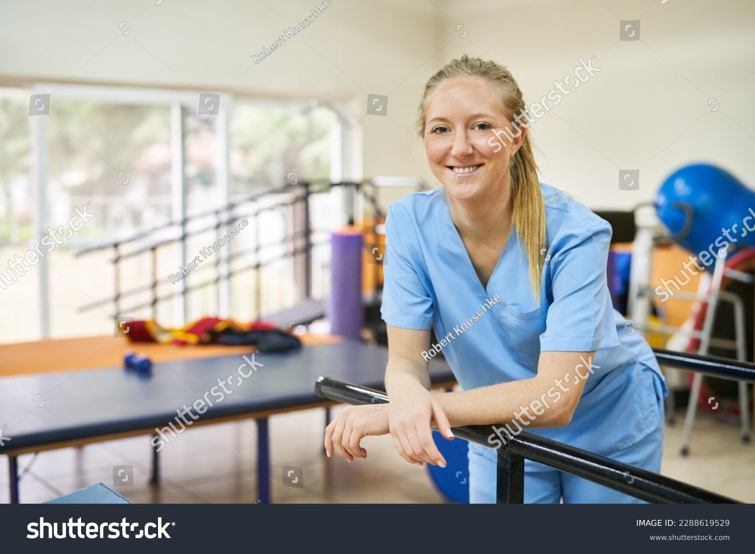 Smiling young woman as physiotherapist standing in gym of nursing home #2288619529