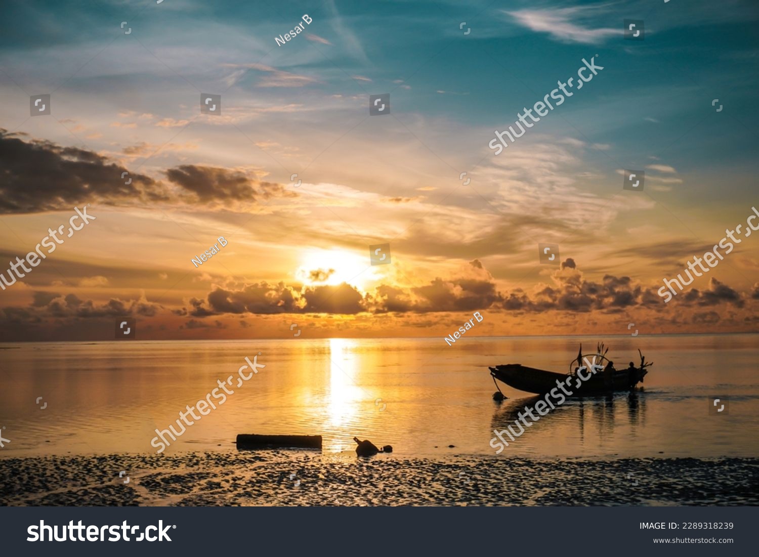 The golden sun rises over the Andaman Sea, casting a warm glow over the tranquil water. A parked boat bobs gently on the ocean, ready for a day of adventure in paradise #2289318239