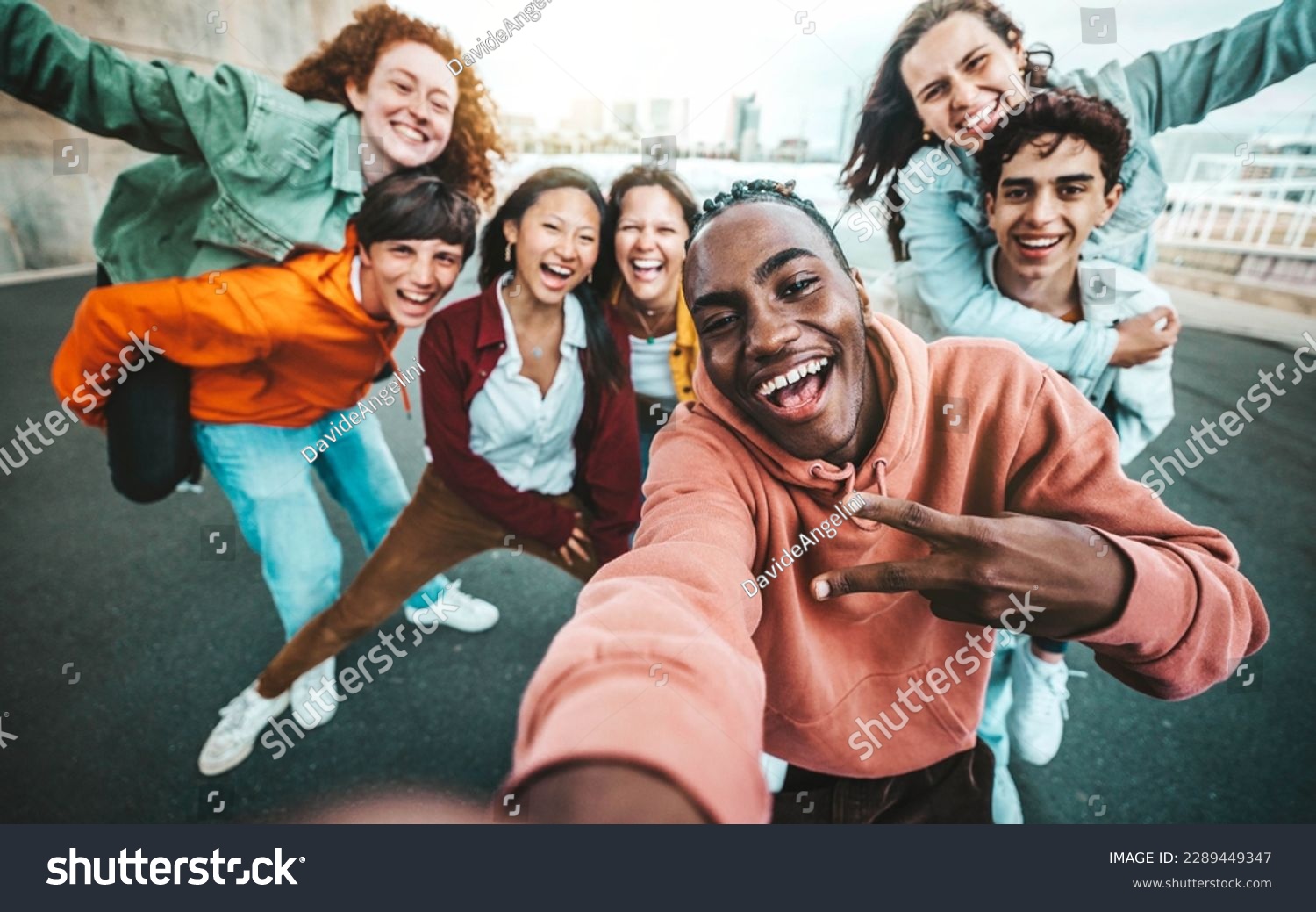 Multicultural group of friends taking selfie picture with smart mobile phone outside - Millenial people walking on city street - Life style concept with guys and girls hanging out together #2289449347