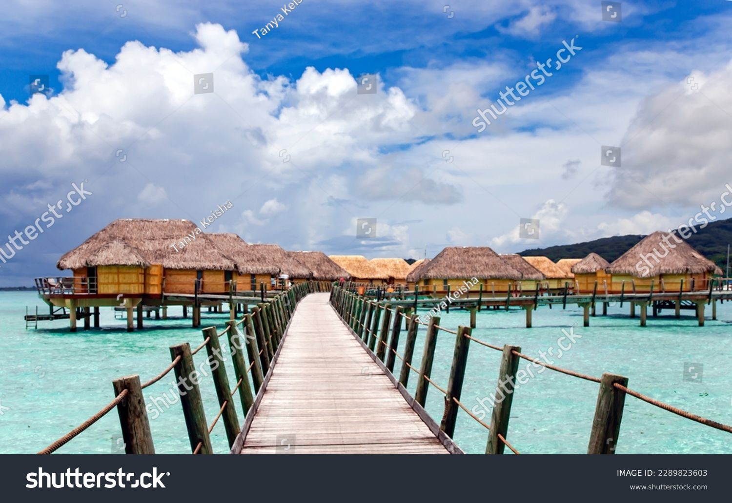 Overwater bungalows stretching and a wooden bridge out across the lagoon in Bora Bora island, Tahiti. Romantic honeymoon destination. #2289823603