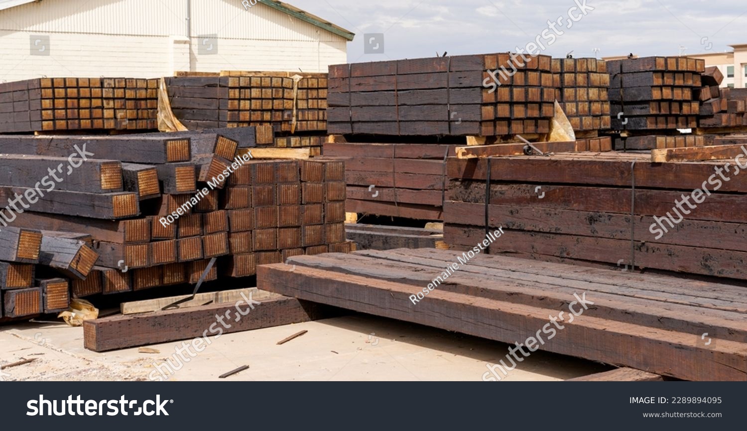 stacked piles of new railroad ties also called railway sleepers with anti-split plates on the ends #2289894095