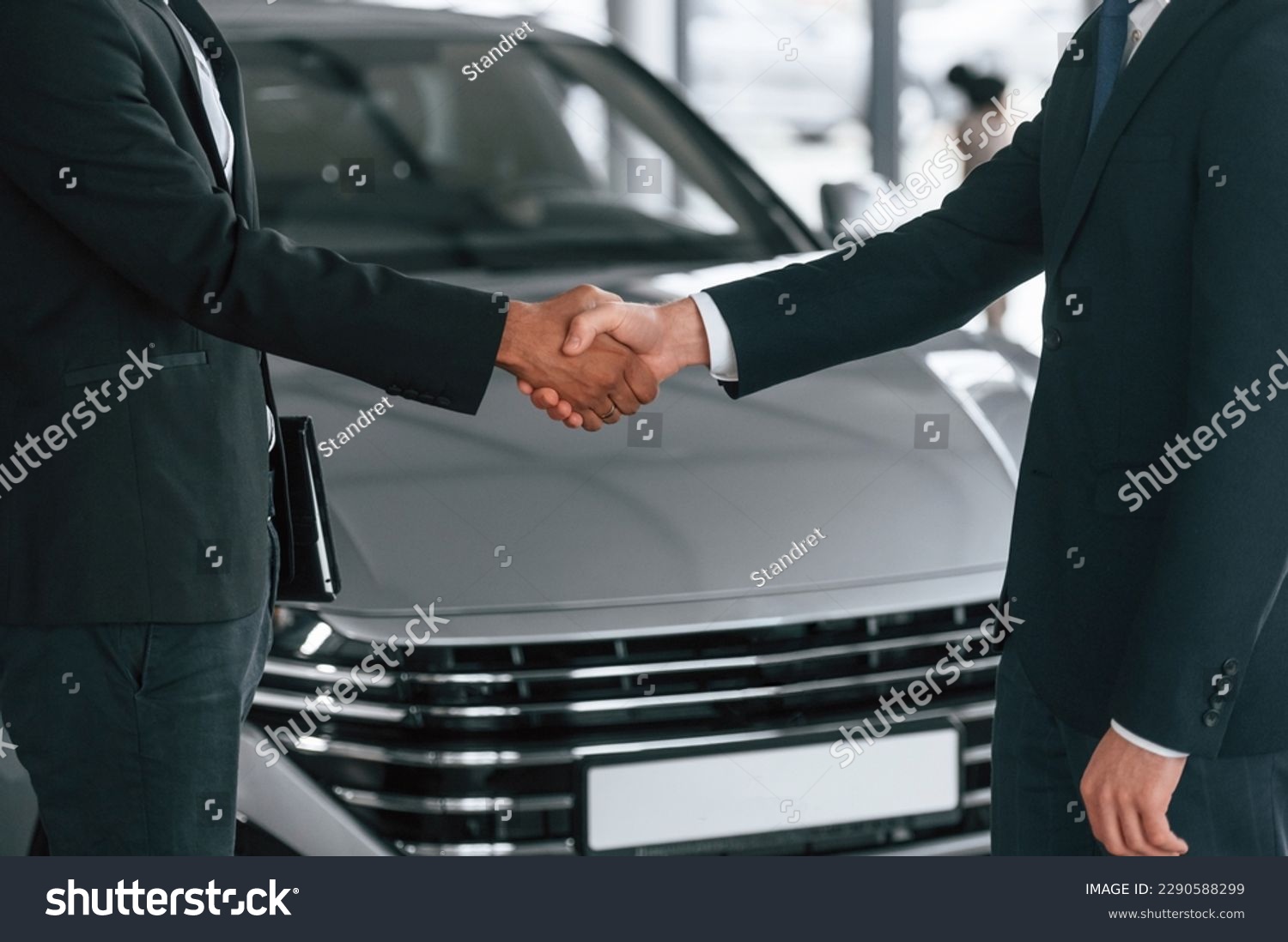 Close up view. Two businessmen are standing in the car showroom and making a deal, handshake. #2290588299