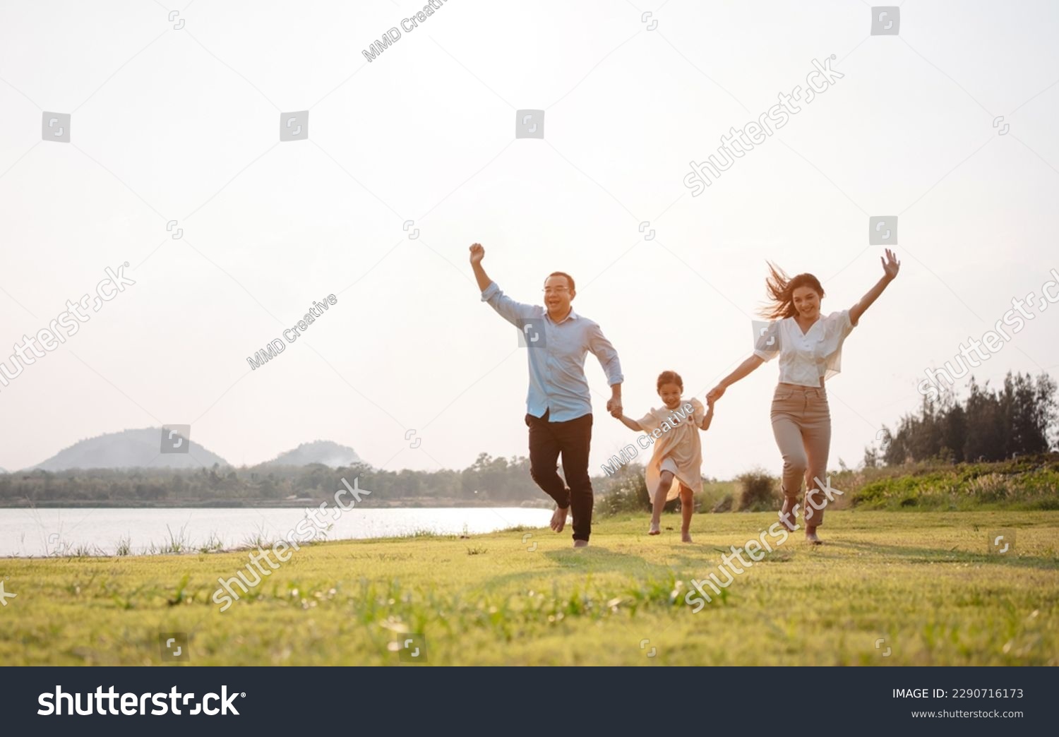 Happy family in the park sunset light. family on weekend running together in the meadow with river Parents hold the child hands.health life insurance plan concept. #2290716173