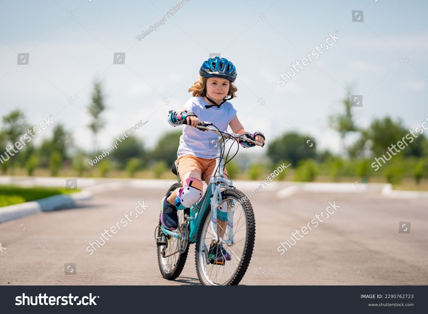 Child in safety helmet riding bike. Boy riding bike wearing a helmet outside. Child in safety helmet riding bike. Little kid boy learns to ride a bike. Kid on bicycle. Happy child in helmet riding a #2290762723