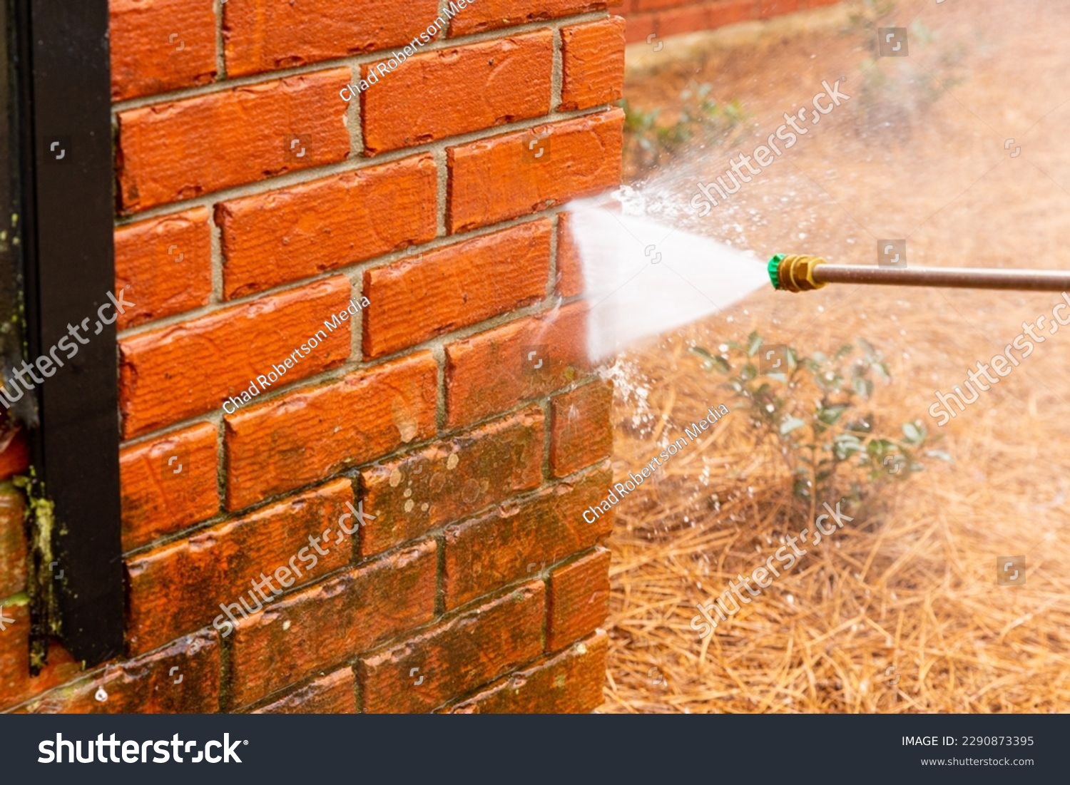 Pressure washer using water to clean a dirty brick wall on a house. #2290873395
