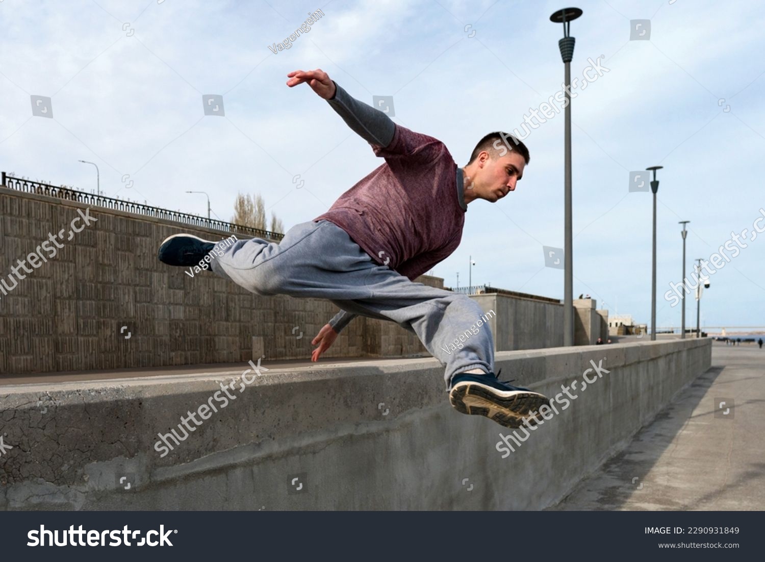 Sports man doing parkour. Parkour athlete training in city in sportive clothes. Free runner jumping have workout at daytime. #2290931849