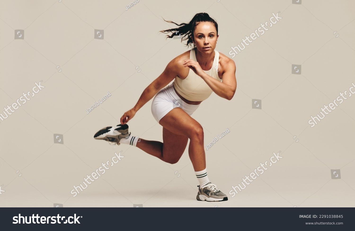 Young female athlete performing strength training exercises in a studio. Sportswoman showing her dedication to improving her body fitness and performance through intense workout techniques. #2291038845