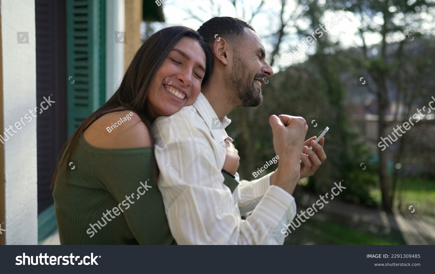 Happy couple celebrating success together. Girlfriend embraces elated boyfriend feeling triumphant. Successful man and woman showing support and happiness #2291309485