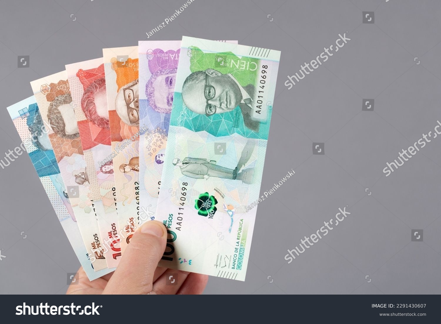 Colombian money - Pesos in the hand on a gray background  #2291430607