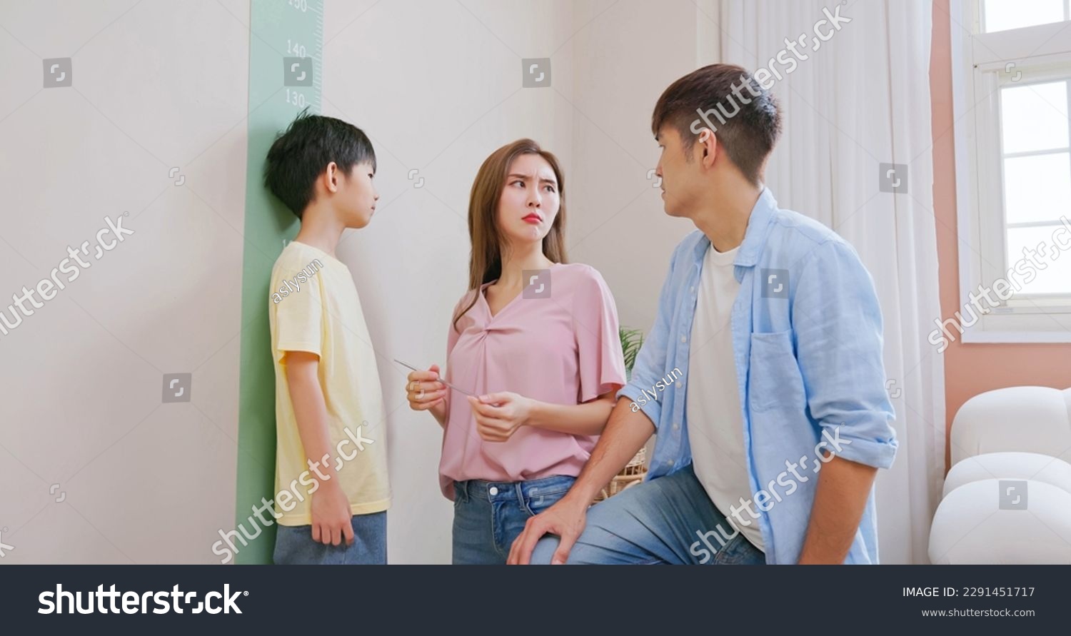 asian parents help their boy doing height measurement with worry about his shortness make them a bit depression #2291451717